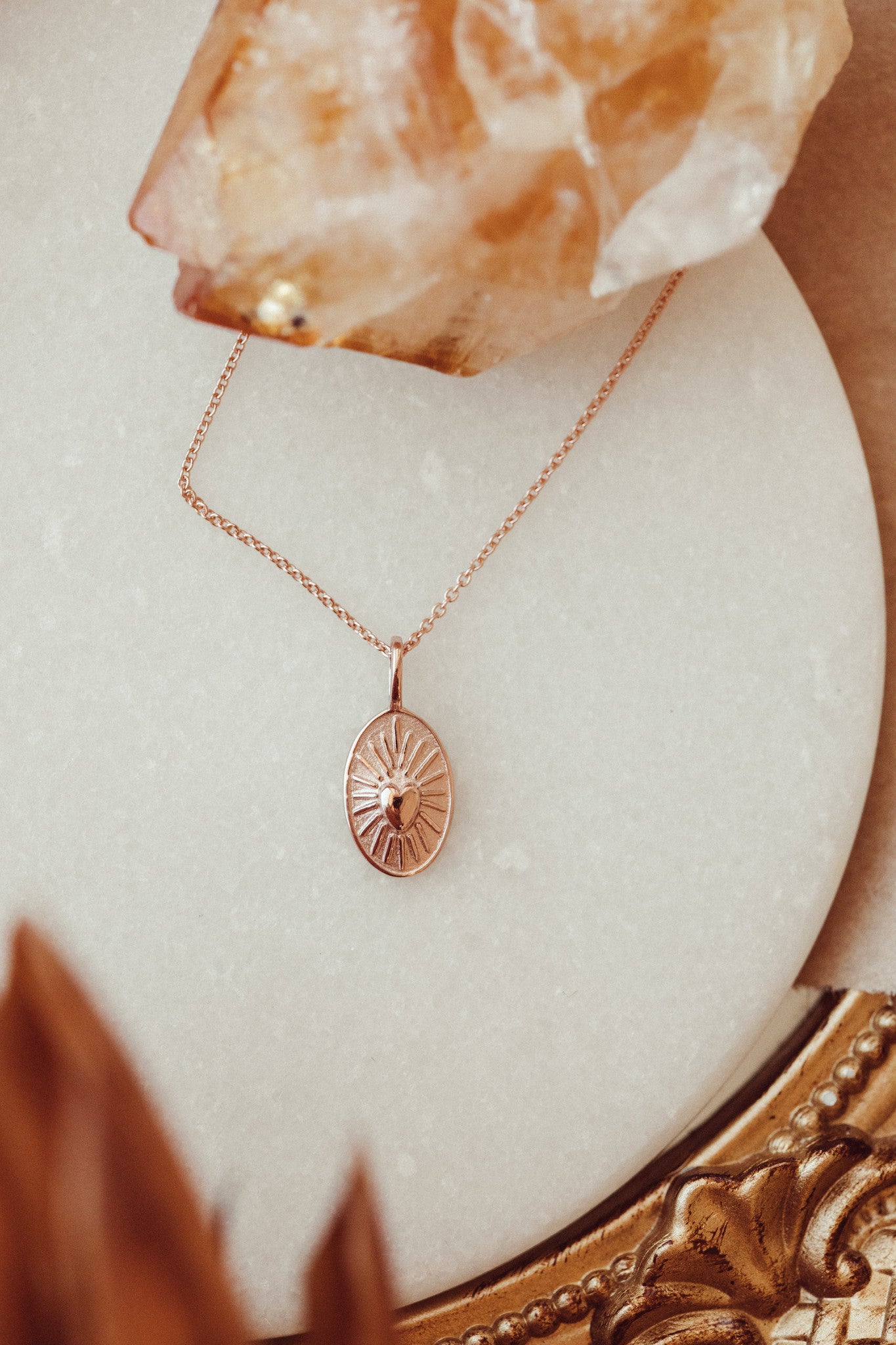 Gold necklace with a heart charm in 14k rose gold on a marble surface