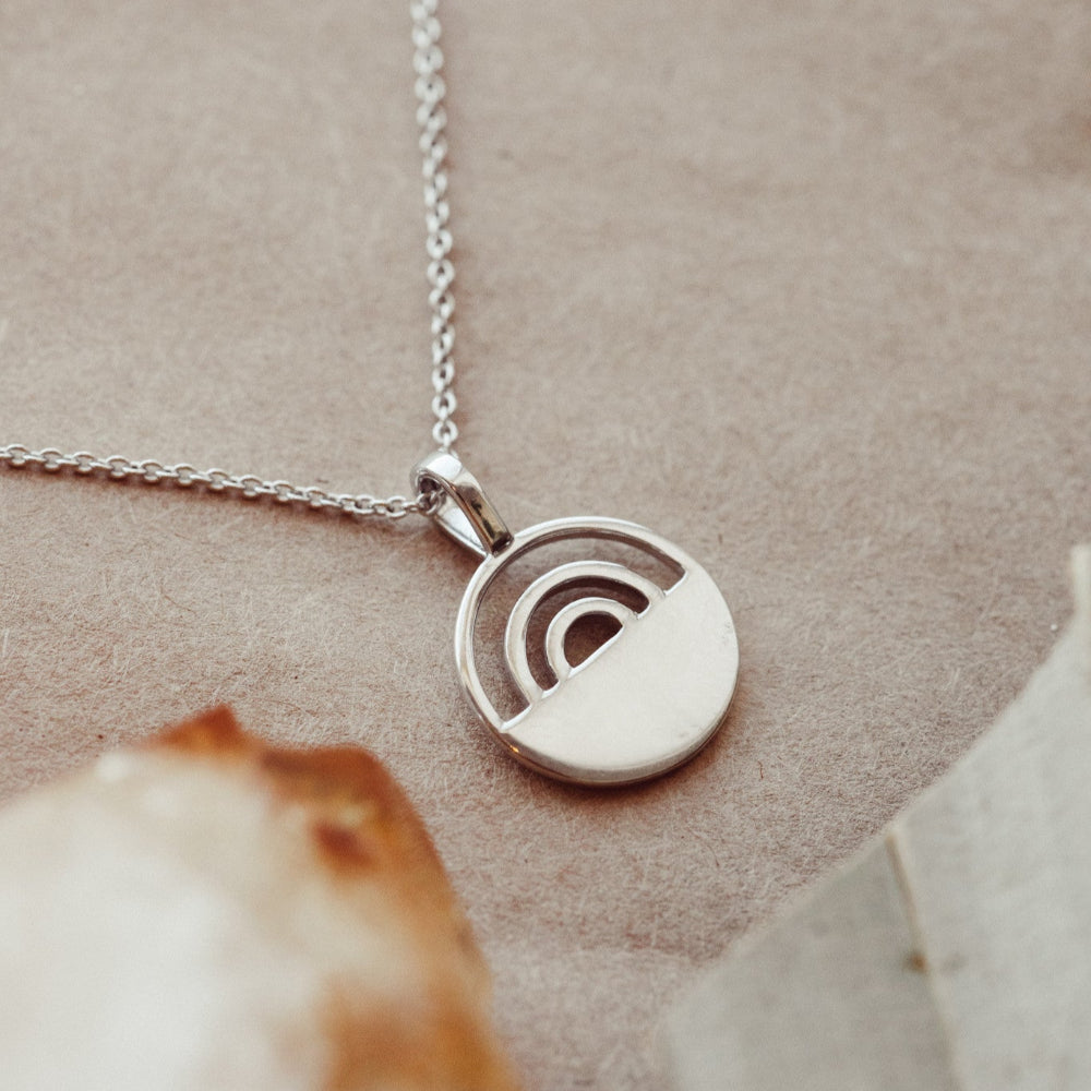 White gold necklace with a circular pendant on a neutral background