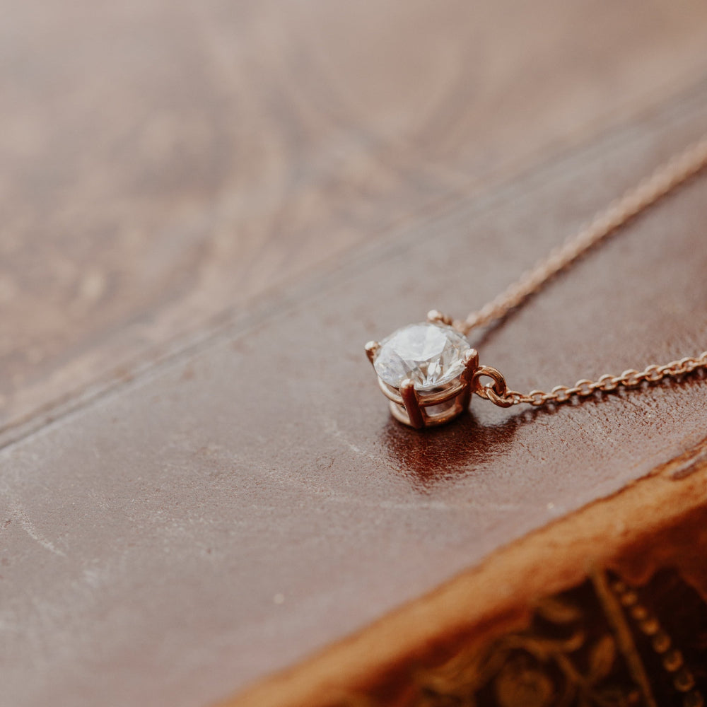 Gold necklace with a diamond pendant on a wooden surface