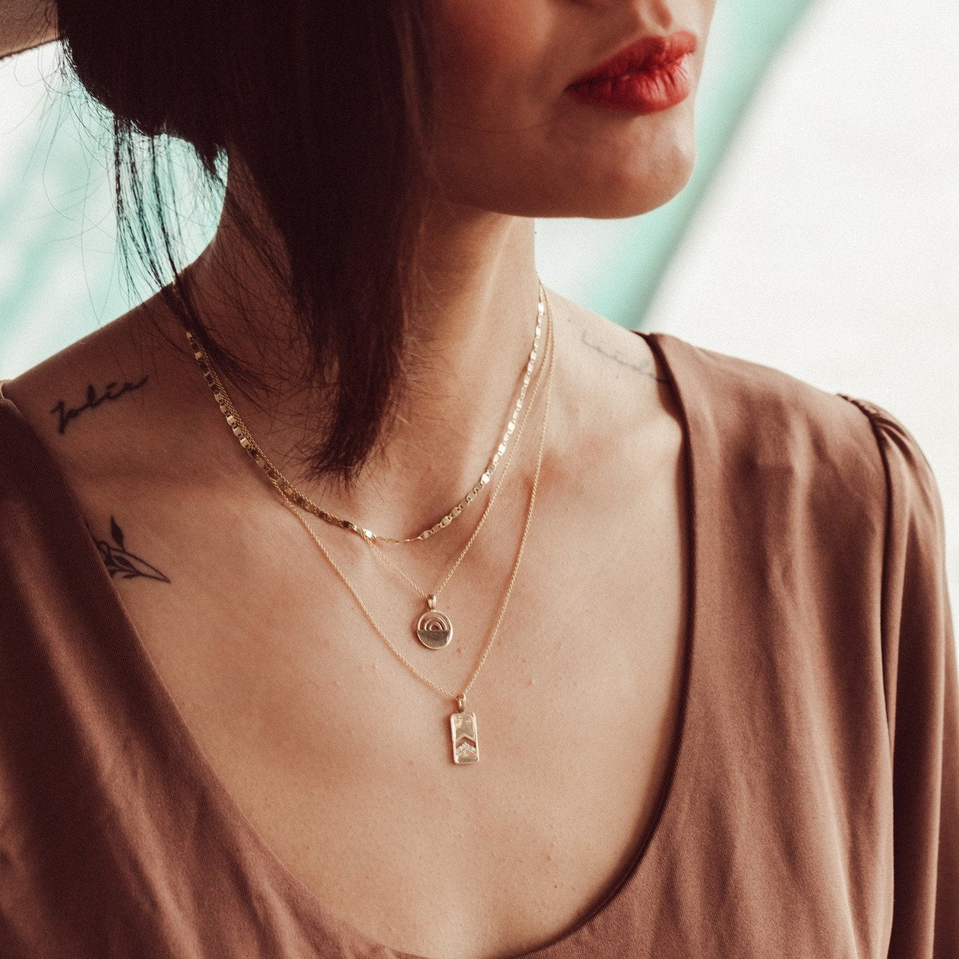 A 14k gold necklace with a rectangle pendant and round pave diamonds, displayed on a rolo chain.