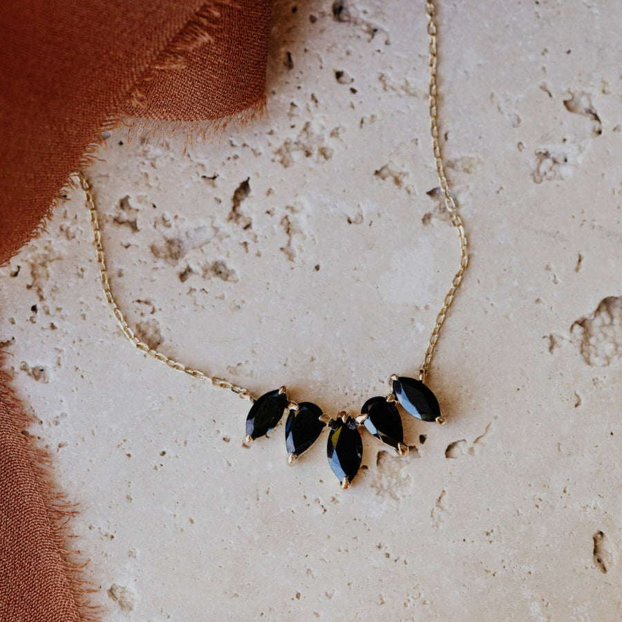 Necklace with black marquise-shaped pendants on a textured surface