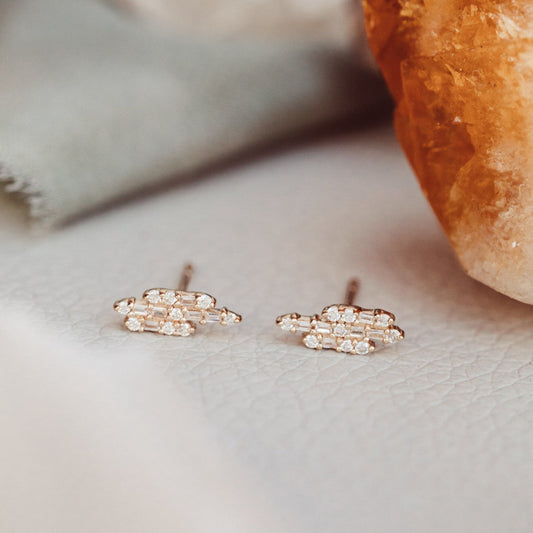 A pair of 14k gold stud earrings featuring alternating baguette and round diamonds set in a staggered bar style, displayed against a neutral background.