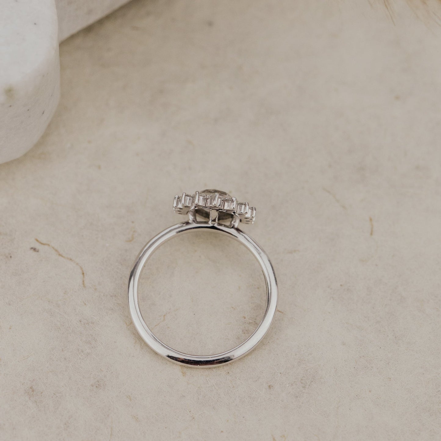 White gold ring with a rustic diamond on a beige surface.
