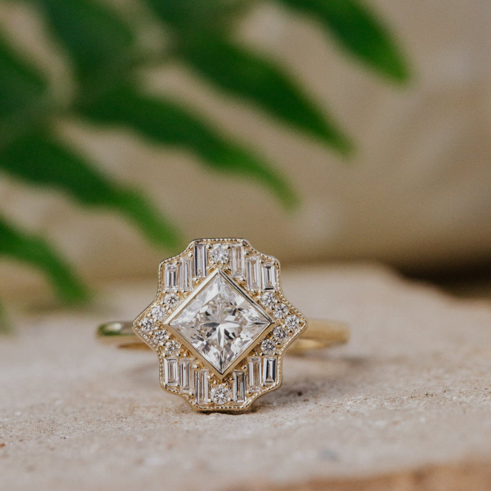 Gold diamond halo ring with baguette stones on a natural background