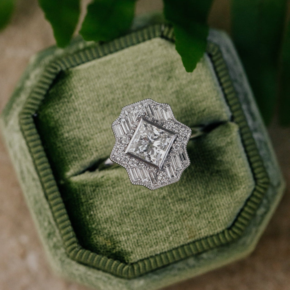 white gold ring with a diamond halo  on a green cushioned jewelry box