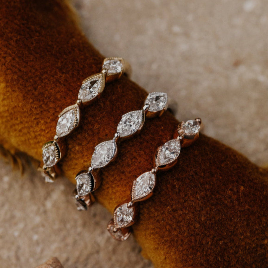 Rose, white, and yellow gold diamond bands on a textured brown surface