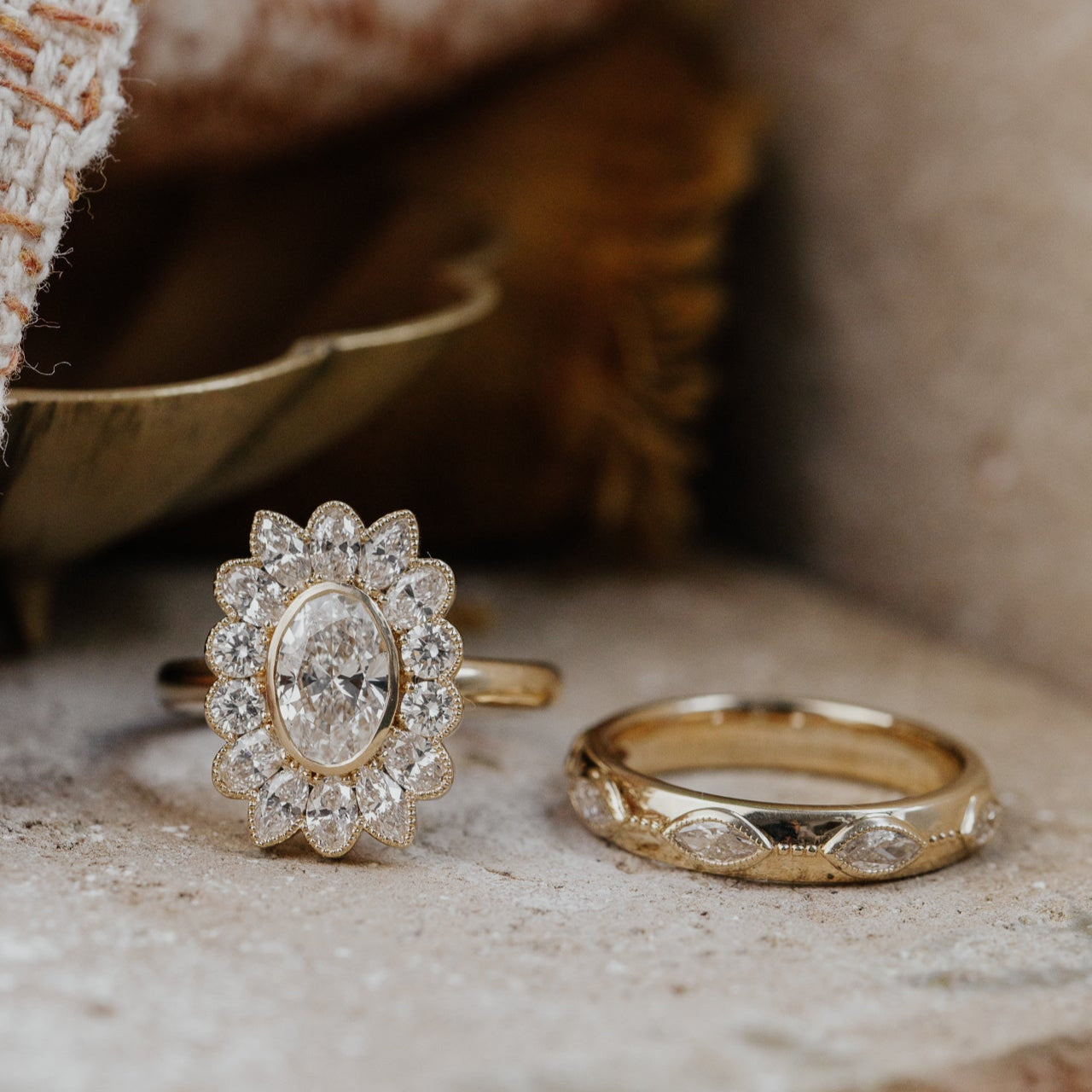 Two gold diamond rings with intricate designs on a textured surface.