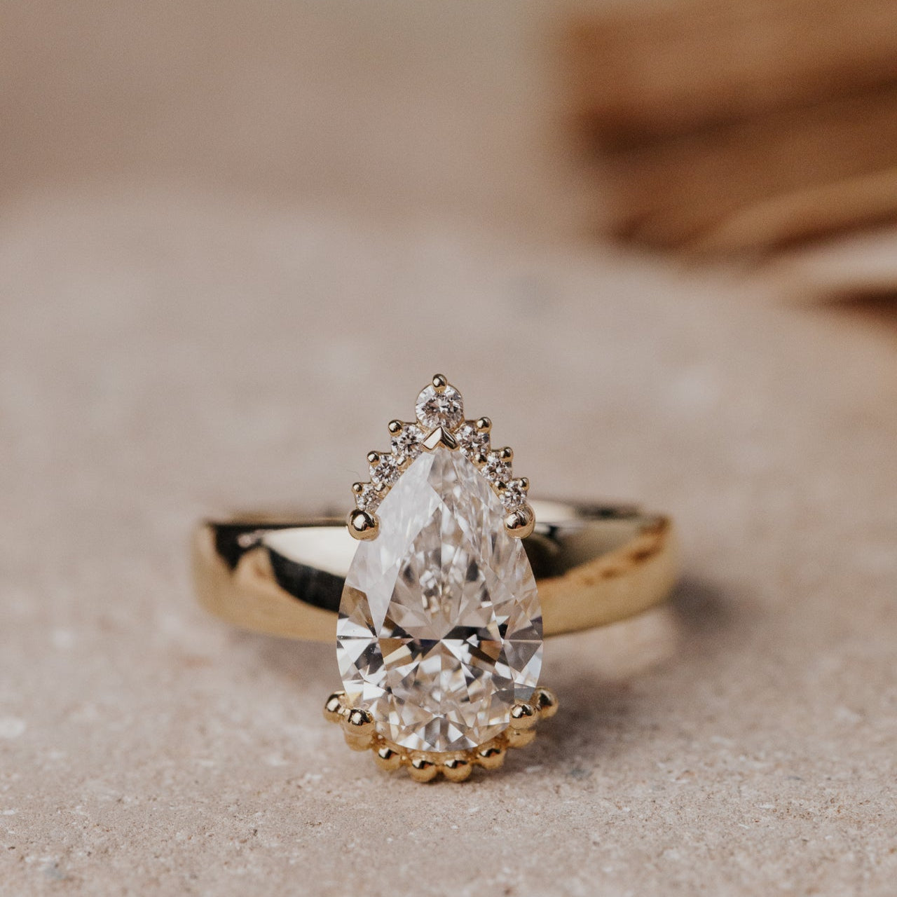 Gold ring with a pear-shaped diamond on a textured surface
