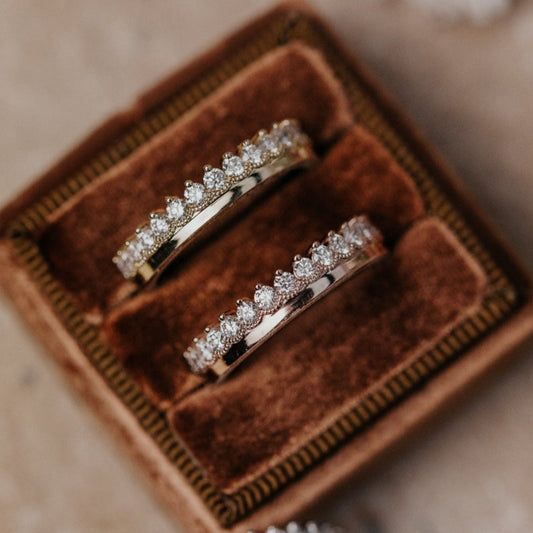 Two diamond rings in a brown velvet box on a soft surface.