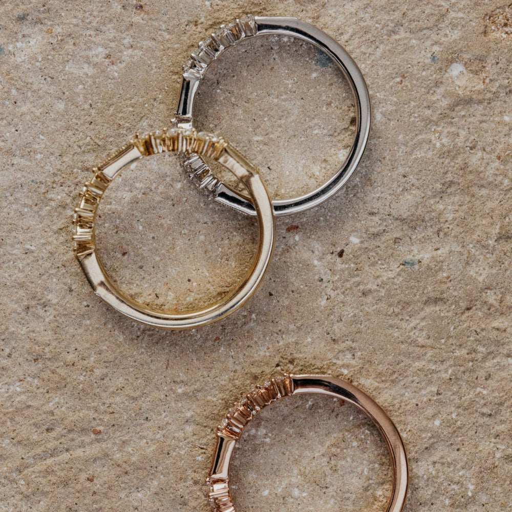 Three gold rings with different designs on a textured surface