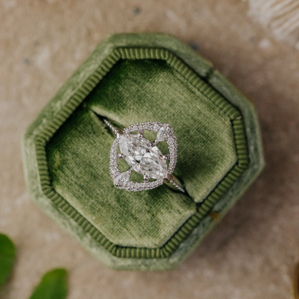 Diamond ring in a green velvet box on a textured surface
