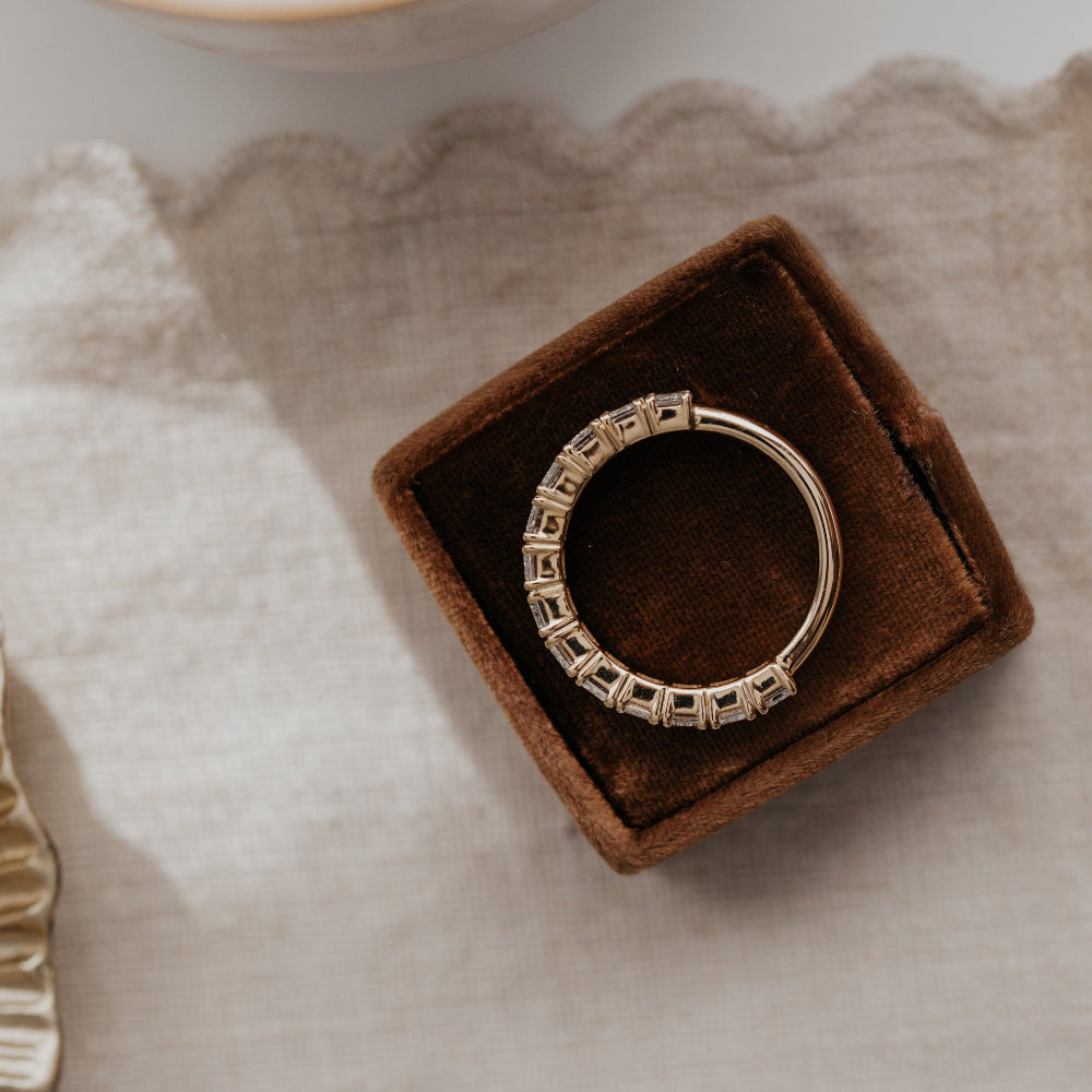 Top-down view of a yellow gold 3/4 diamond eternity band on a brown velvet ring box