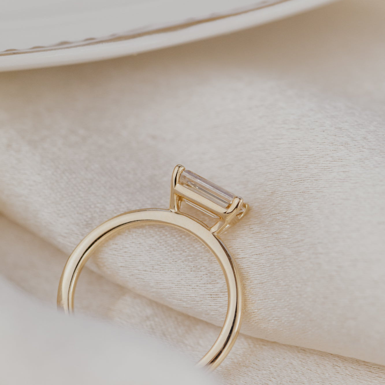 Gold ring with a champagne diamond on a soft beige background.