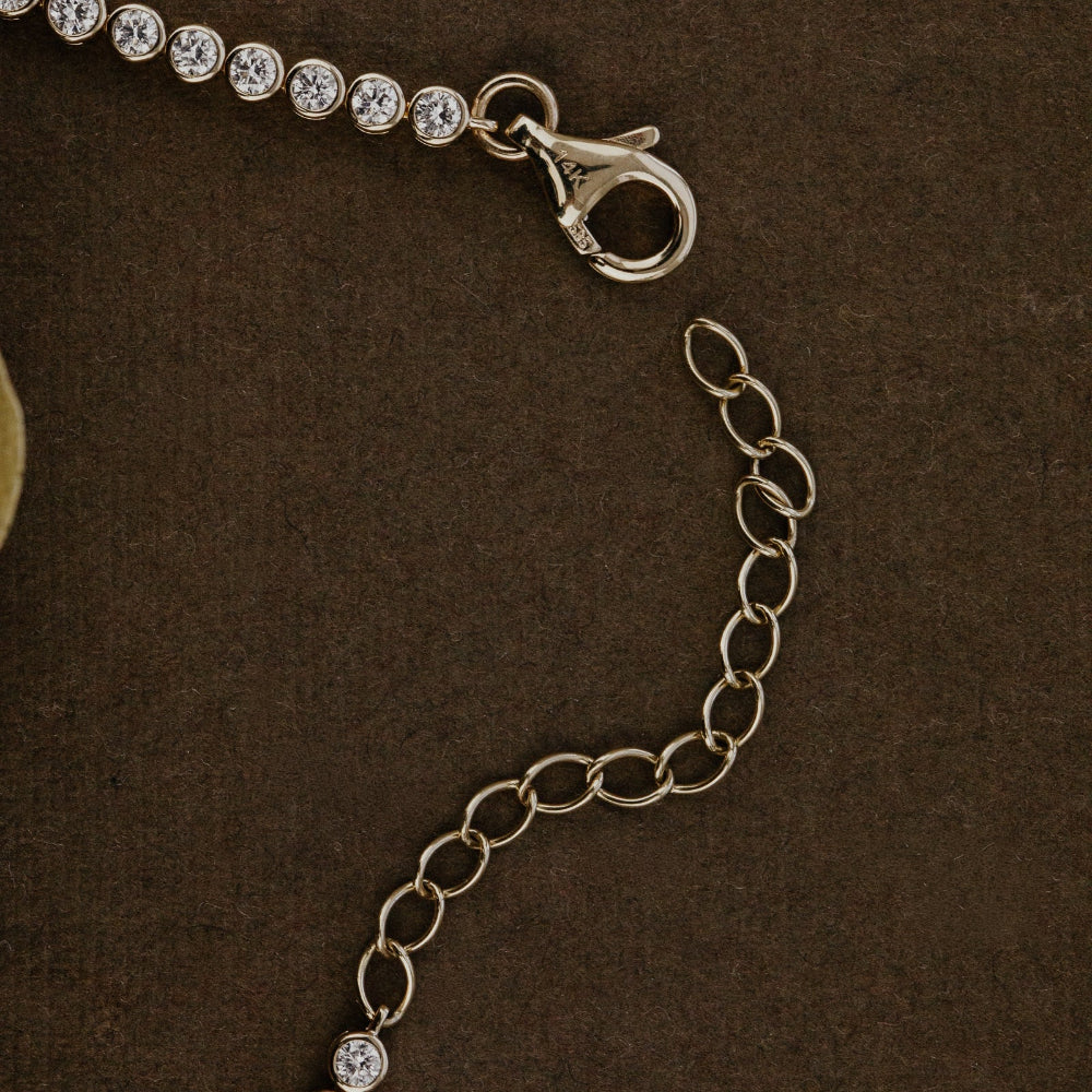 Close-up of a gold necklace with a clasp on a brown background