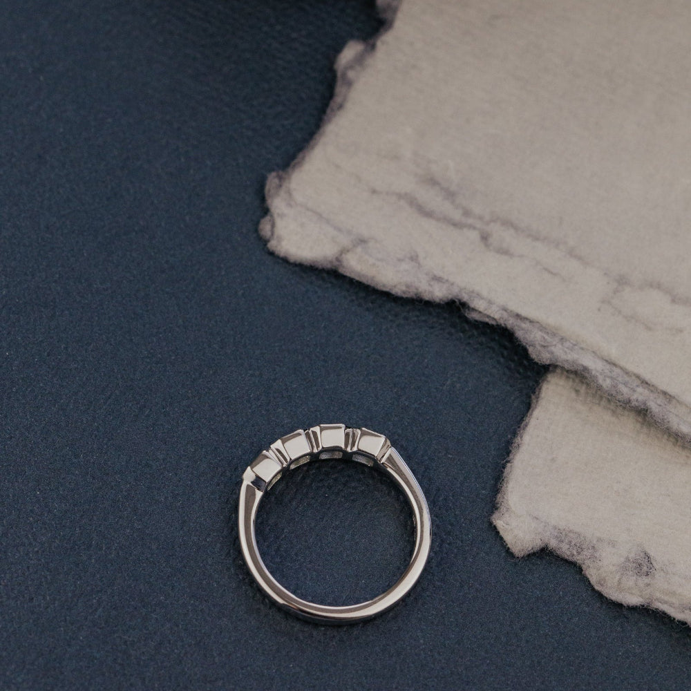 White gold ring on a textured surface with a dark background.