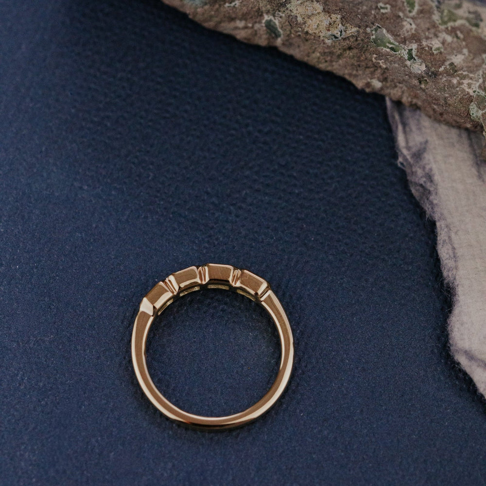 Gold sapphire ring on a textured blue surface.