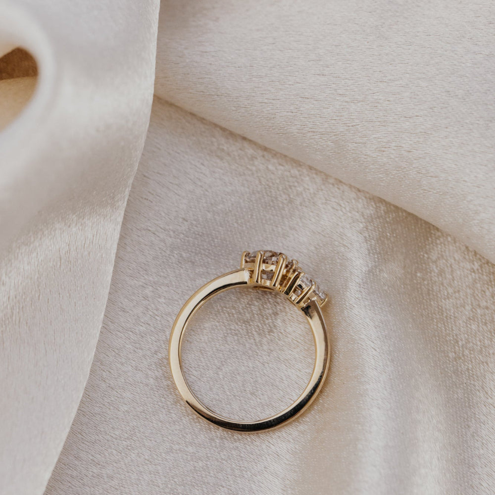 Gold toi et moi ring with champagne and lab grown diamonds on a soft beige fabric background.