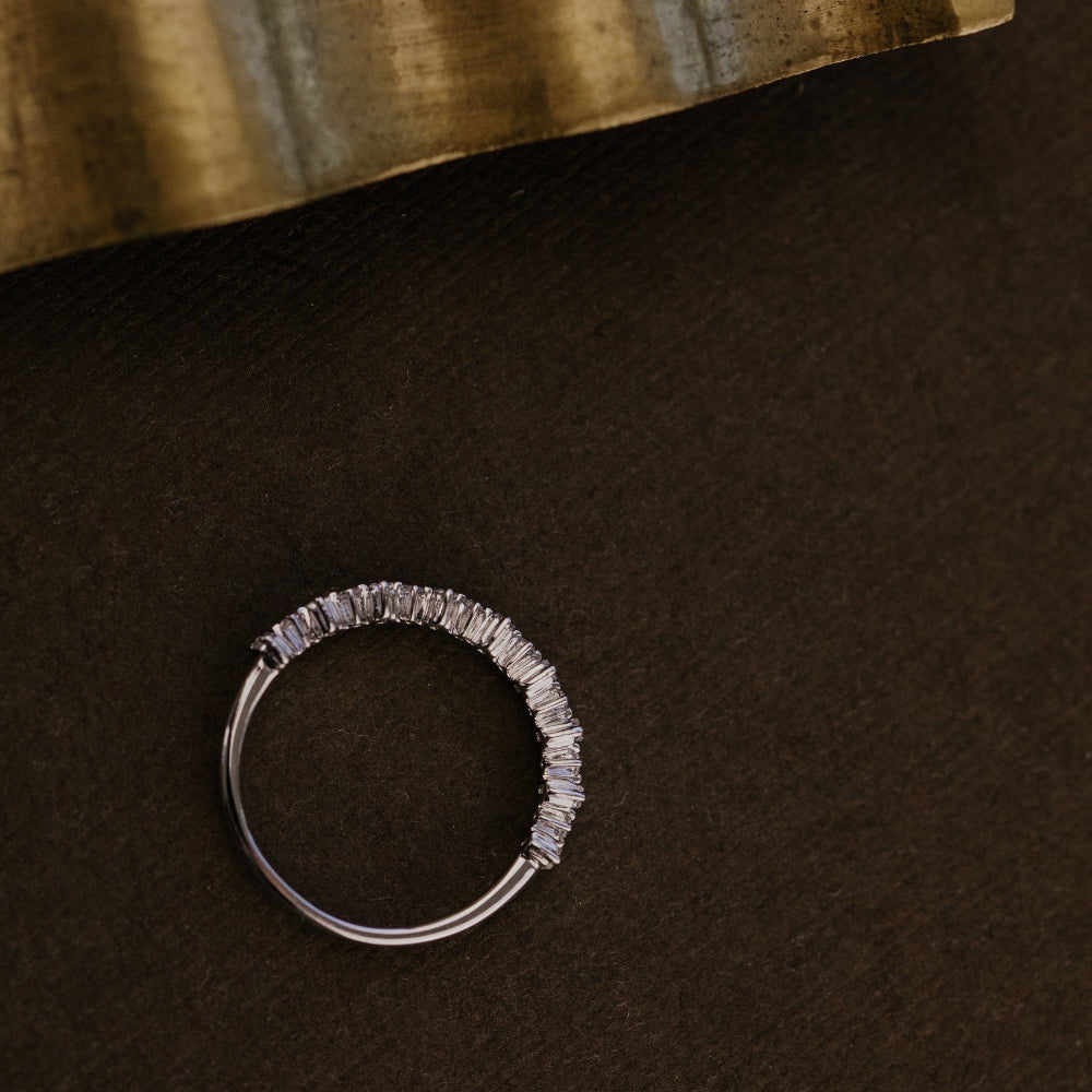 White gold wedding band on a dark brown surface