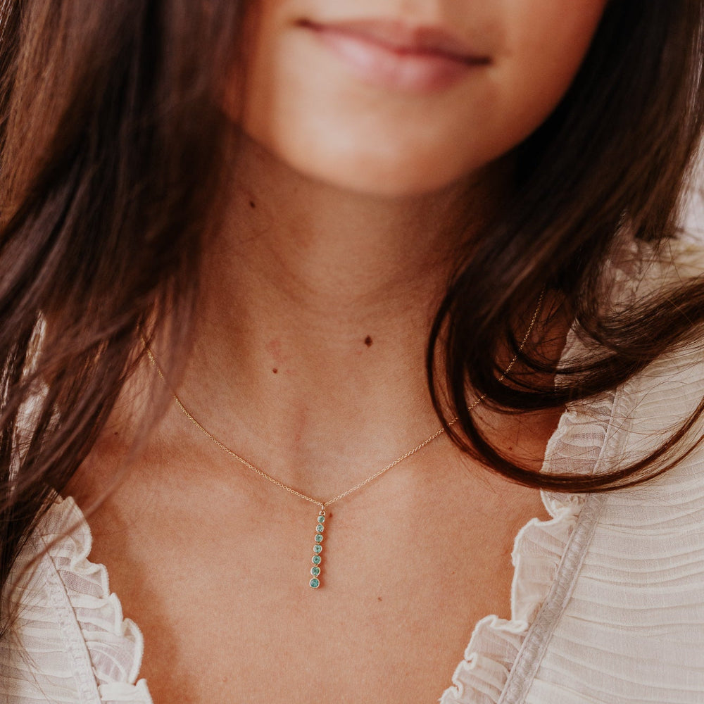 Close-up of a woman wearing a delicate necklace with a blurred background