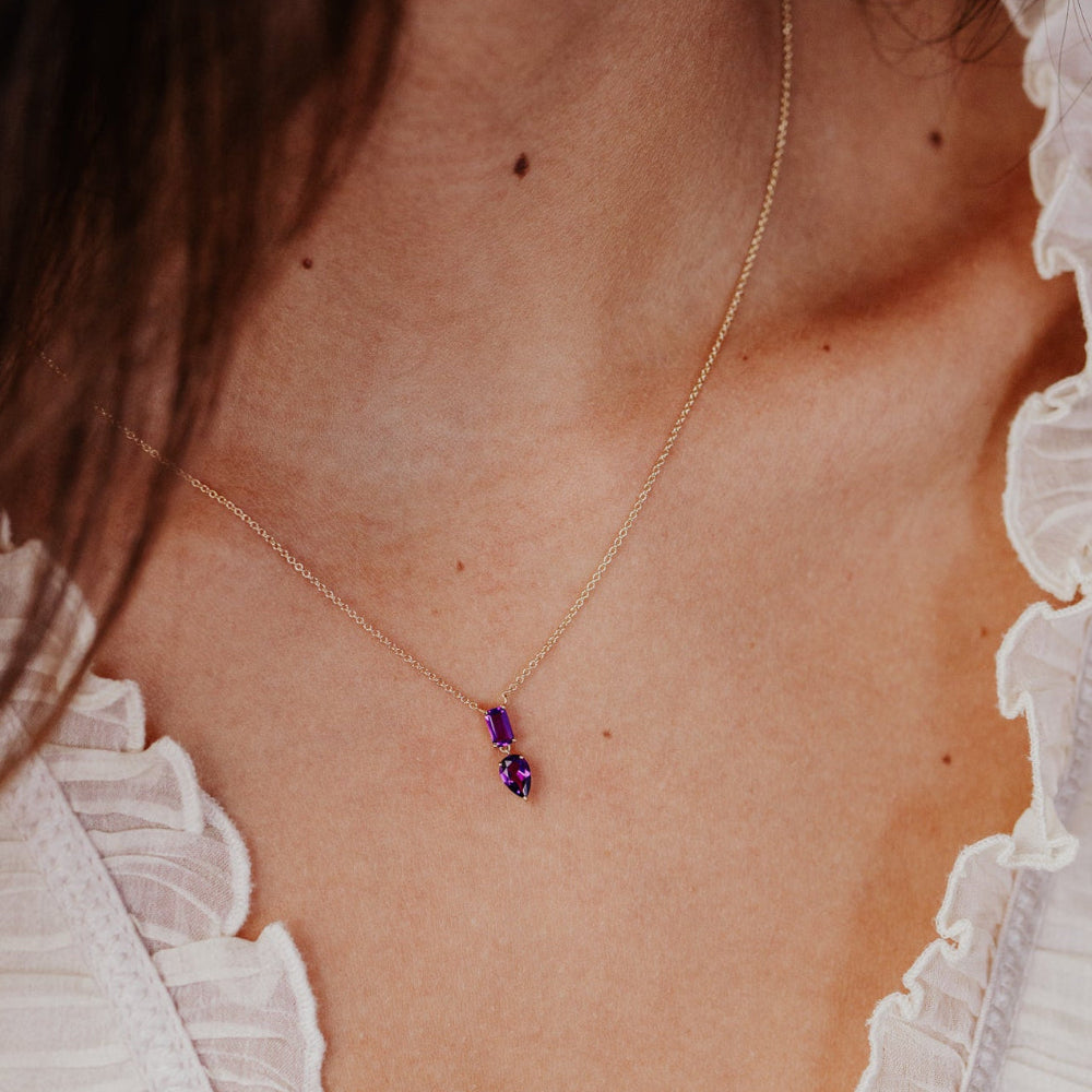 Necklace with purple amethyst gemstones worn by a person with white lace garment