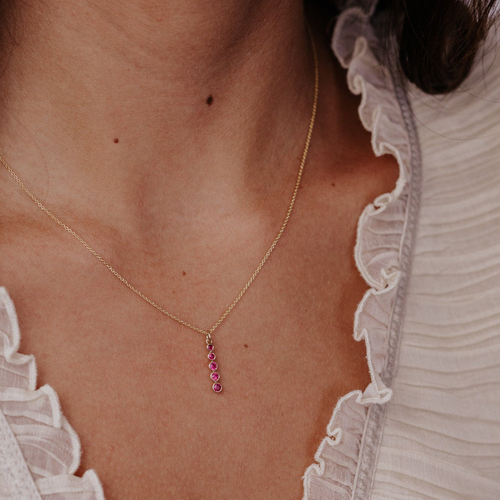 Necklace with red ruby gemstones worn by a person, close-up view.