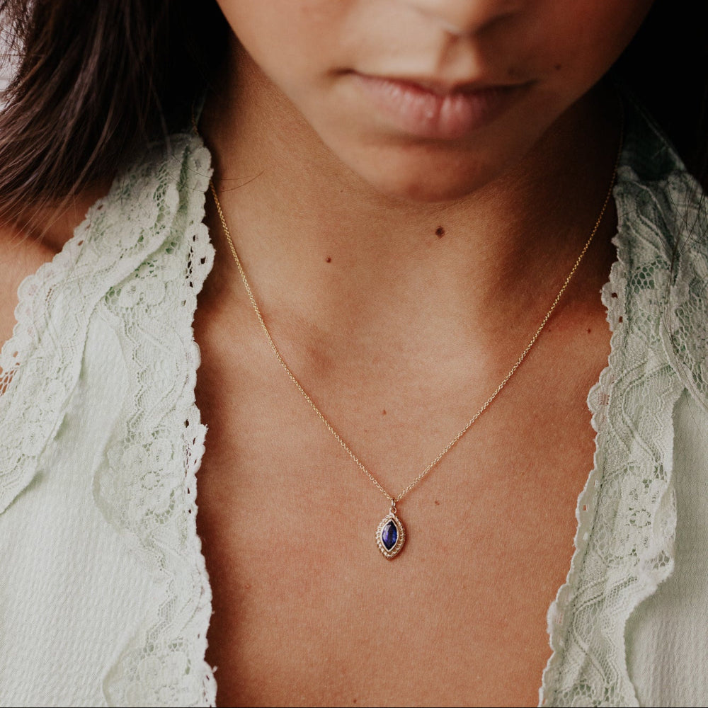 Close-up of a woman wearing a delicate Kyanite necklace with a blue pendant.