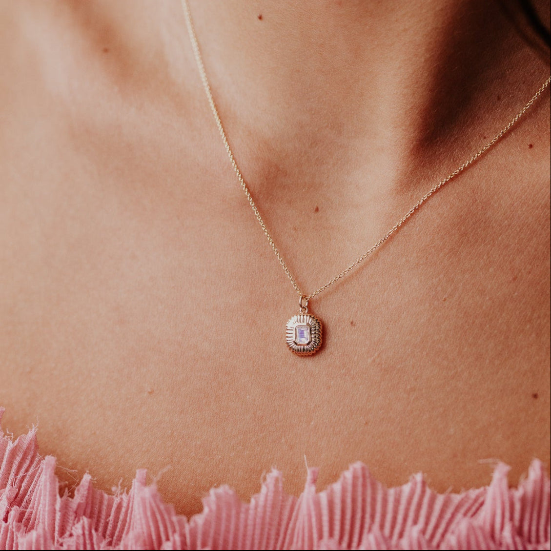 Necklace with a moonstone pendant on a person wearing a pink garment