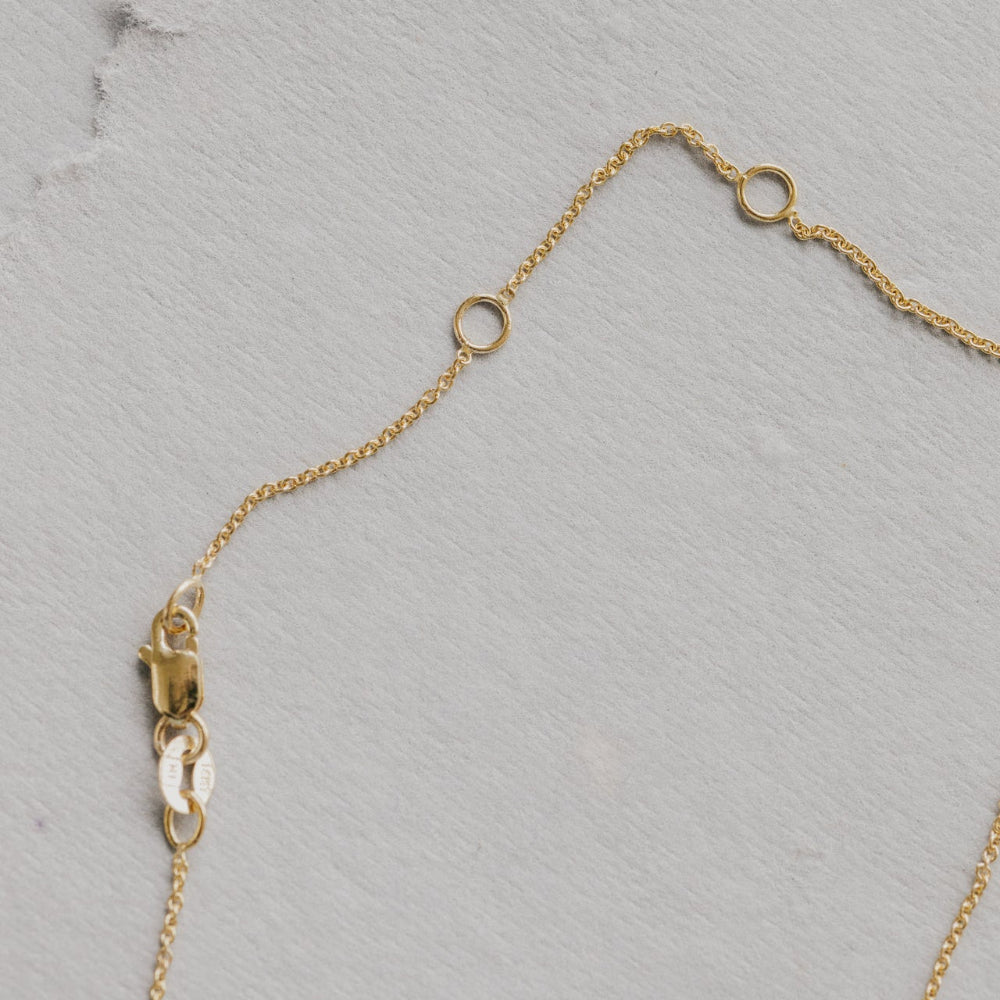 Gold necklace chain on a textured gray surface
