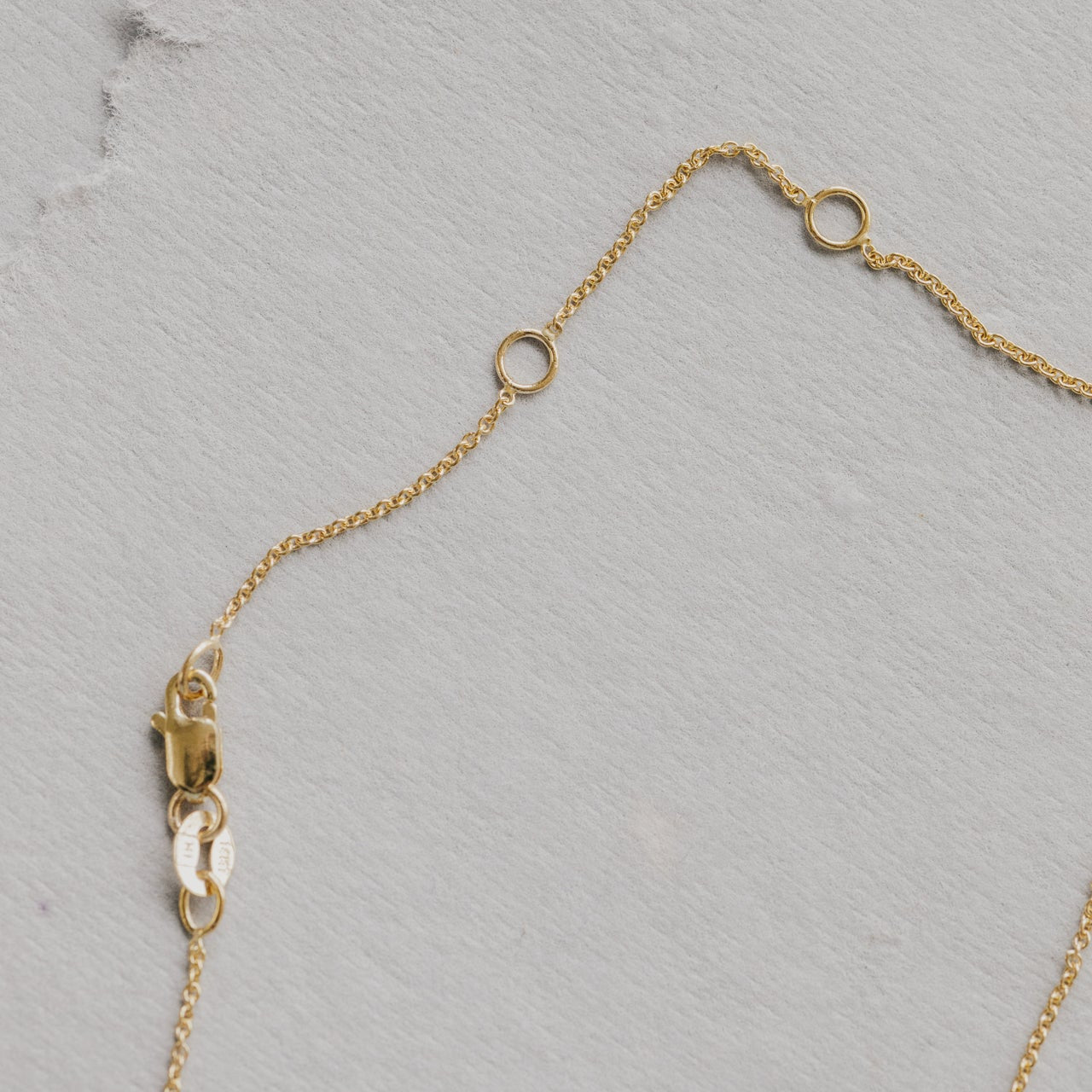 Gold necklace chain on a textured gray surface
