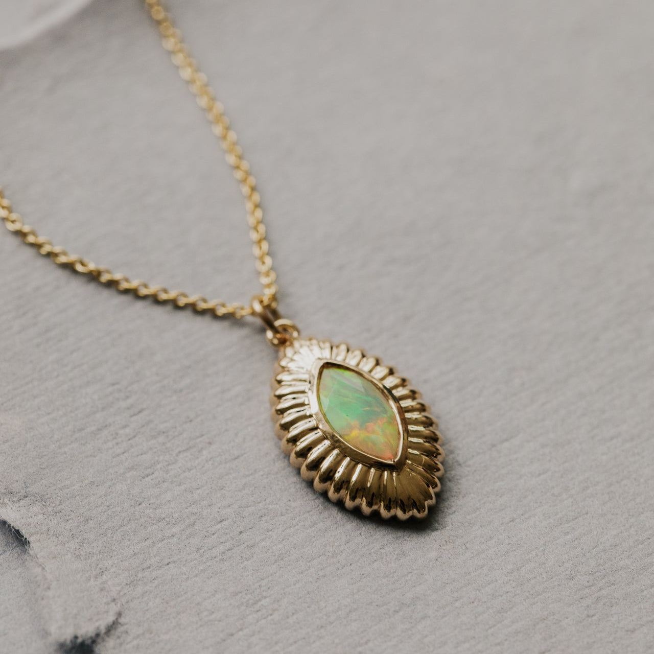 Gold necklace with an opal pendant on a gray surface