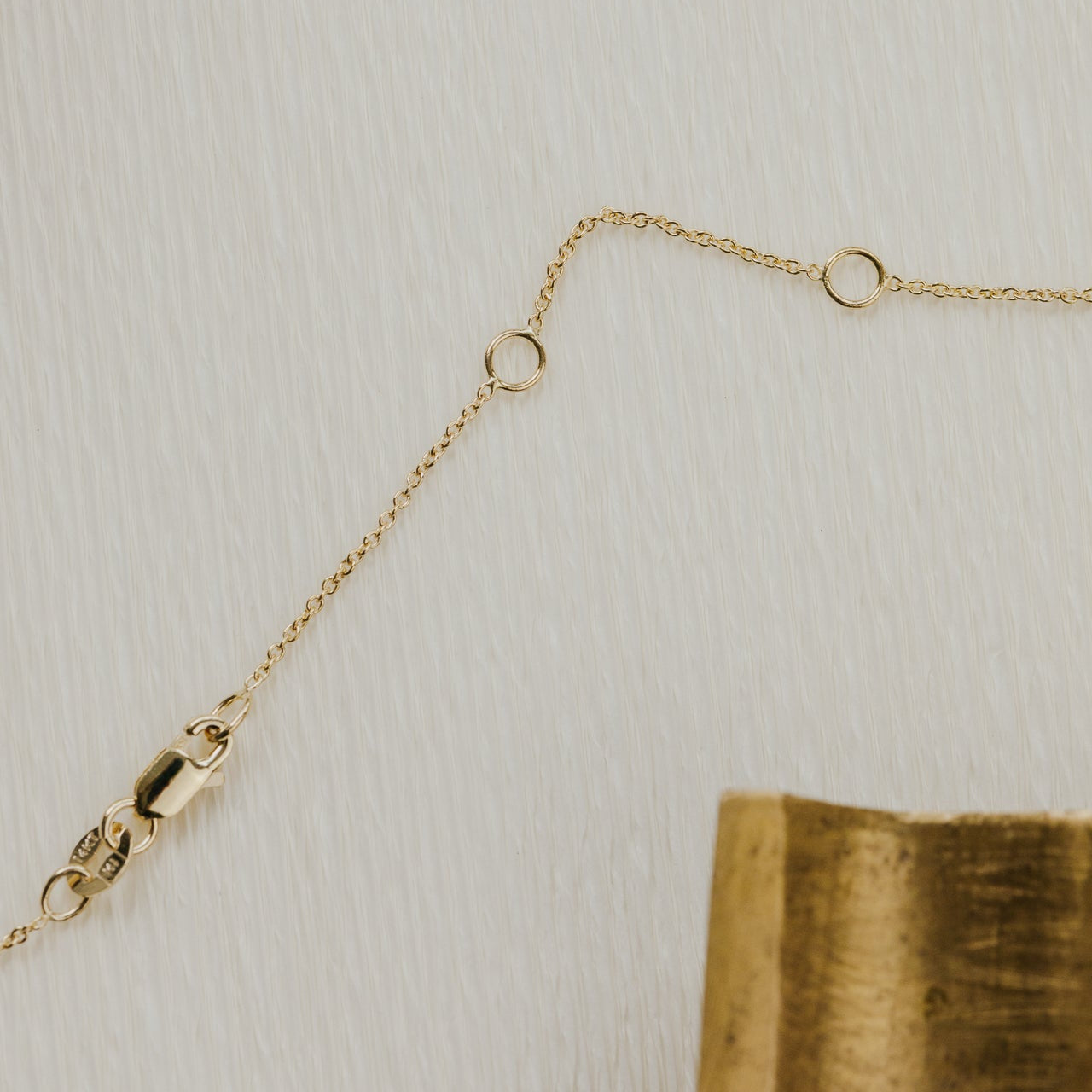 Gold chain necklace on a textured beige surface