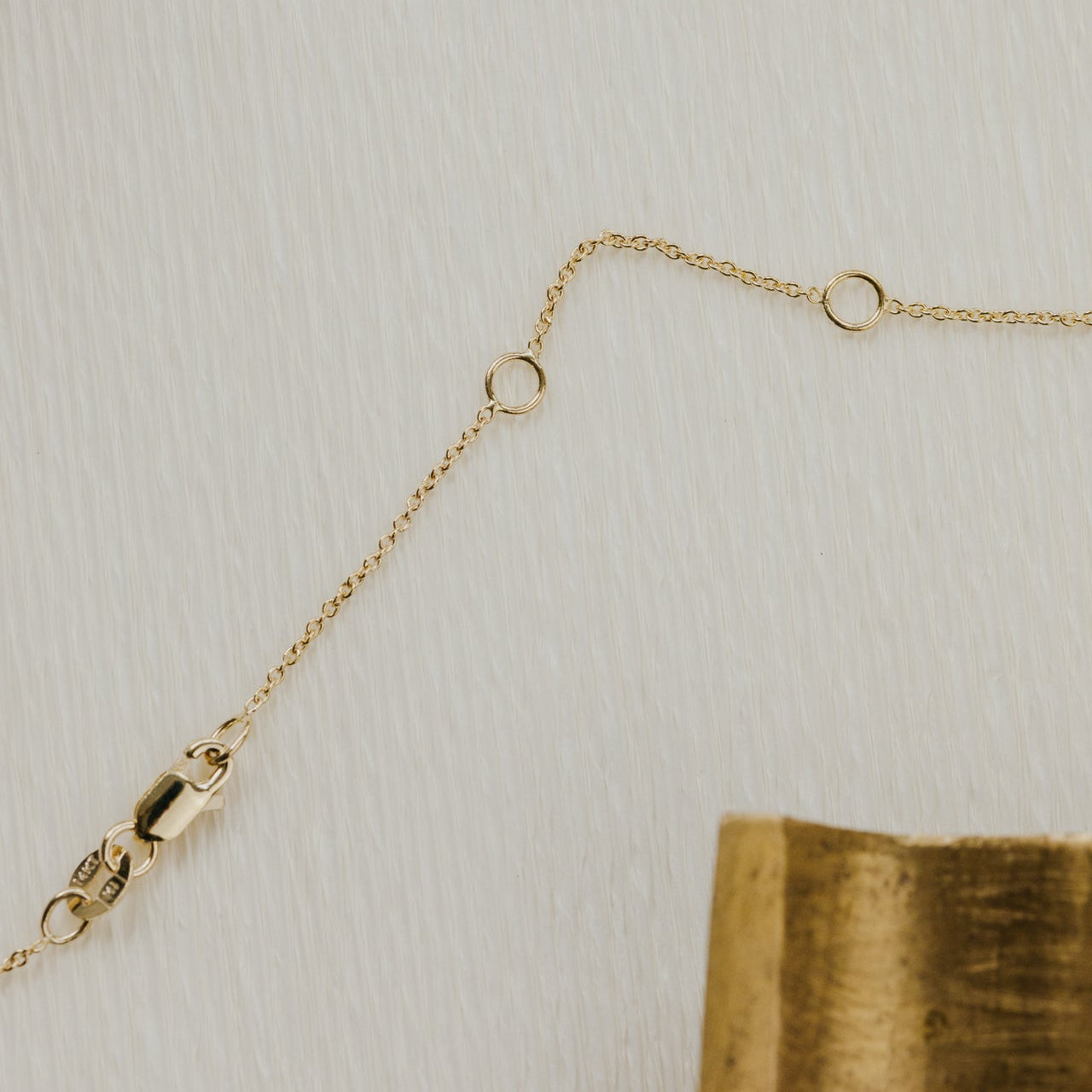 Gold chain necklace on a textured beige background