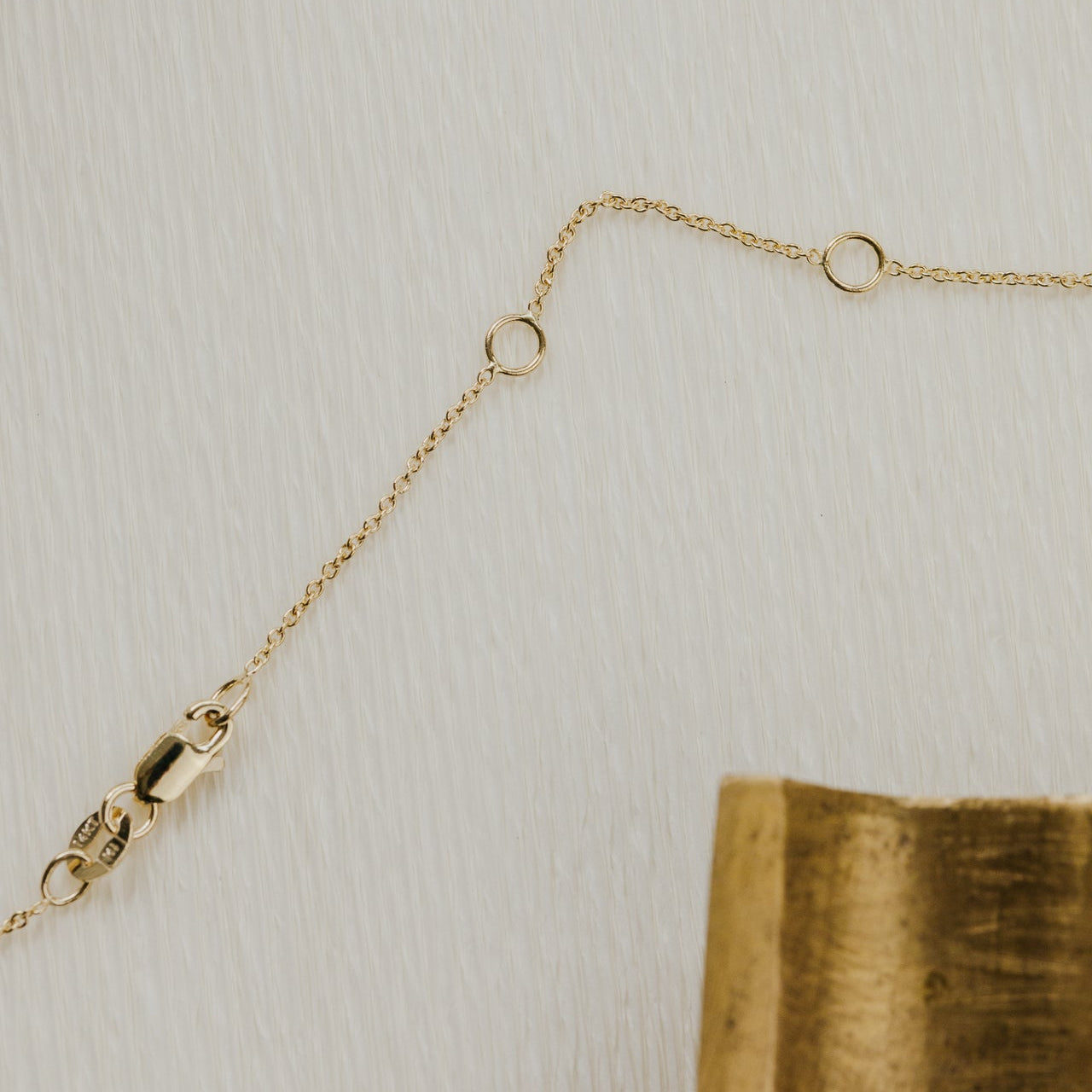 Gold chain on a textured beige surface