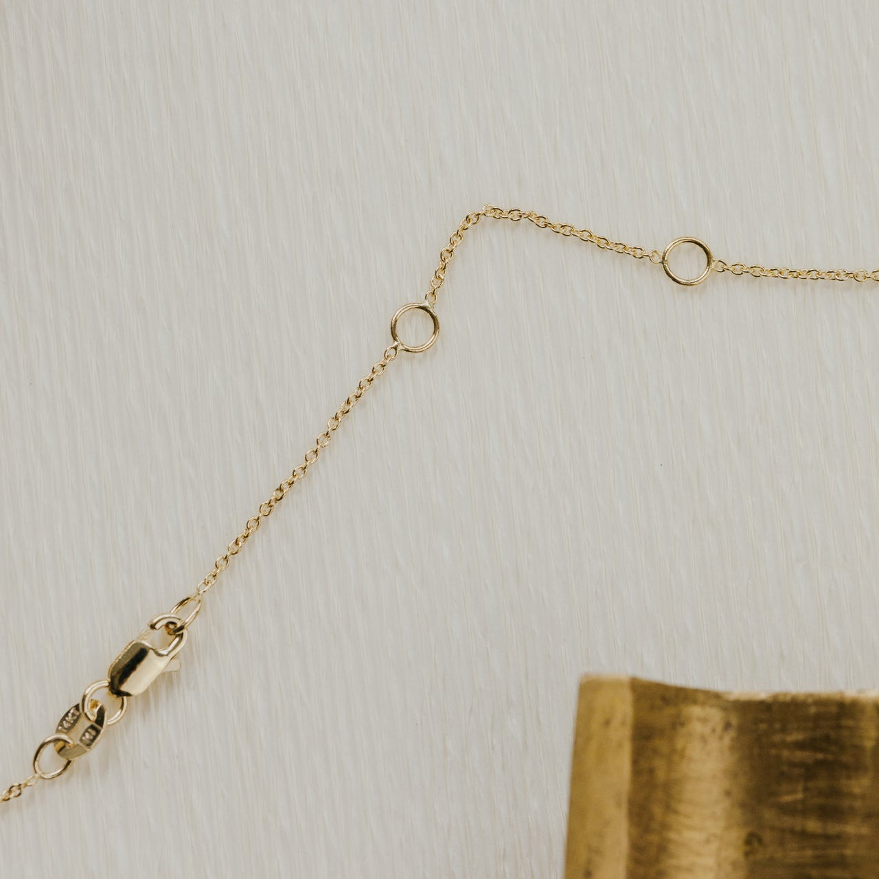 Gold chain necklace on a textured beige surface
