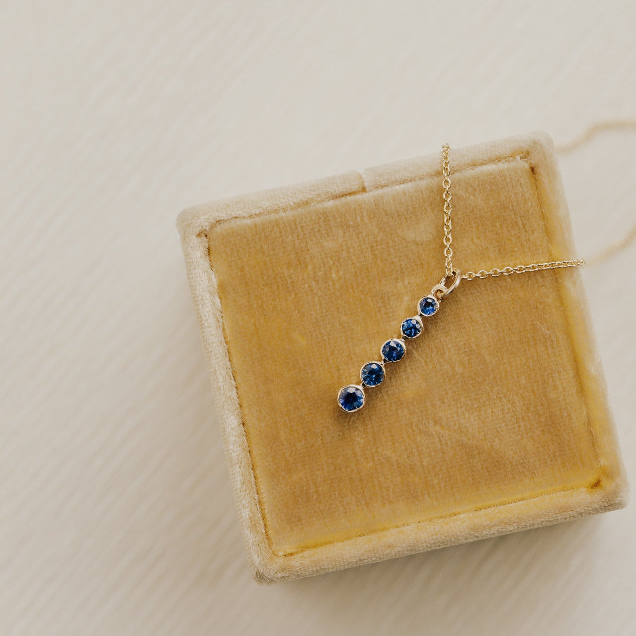Necklace with blue sapphire stones in a yellow jewelry box on a light background