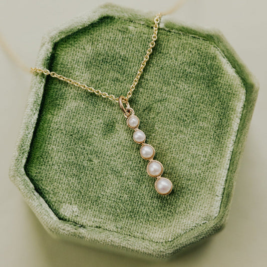 Pearl necklace on a green textured surface