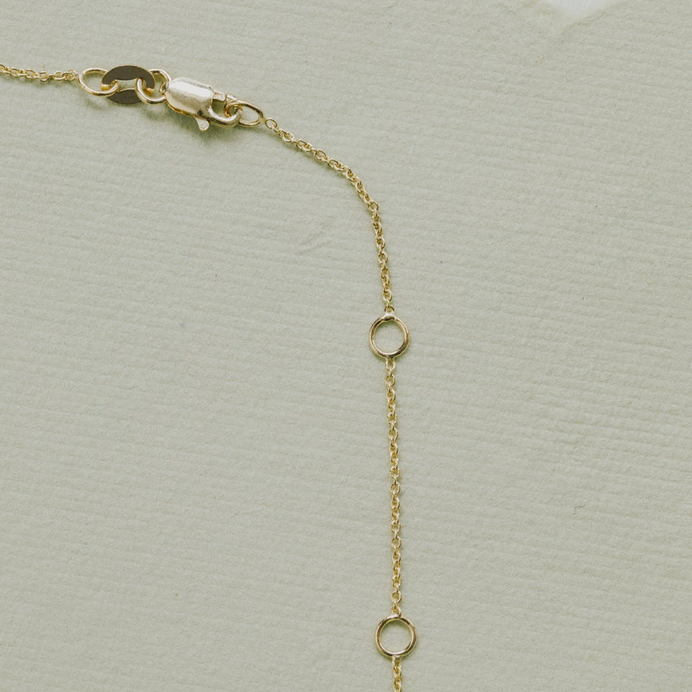Gold chain necklace on a textured beige background