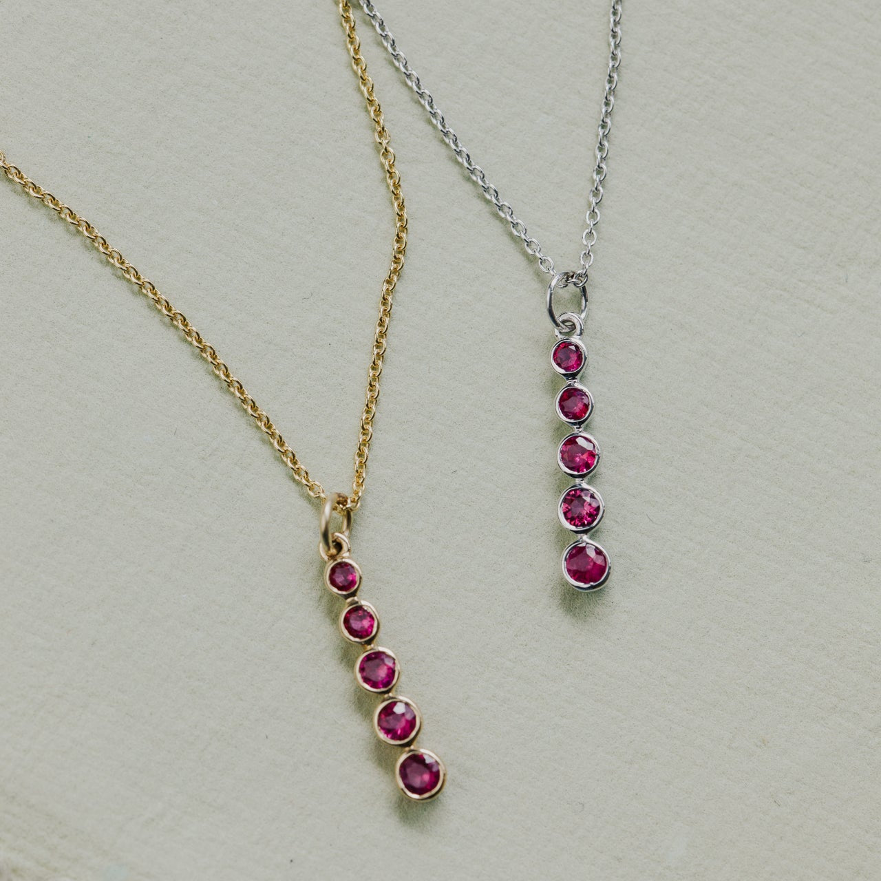 Two necklaces with ruby pendants on a light gray background