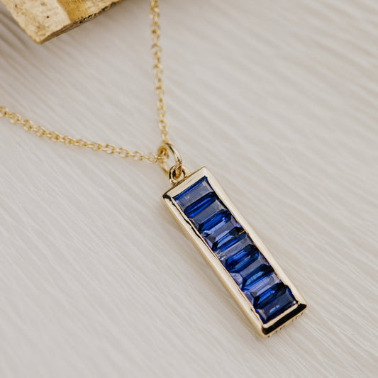 Gold necklace with a blue Kyanite pendant on a light background