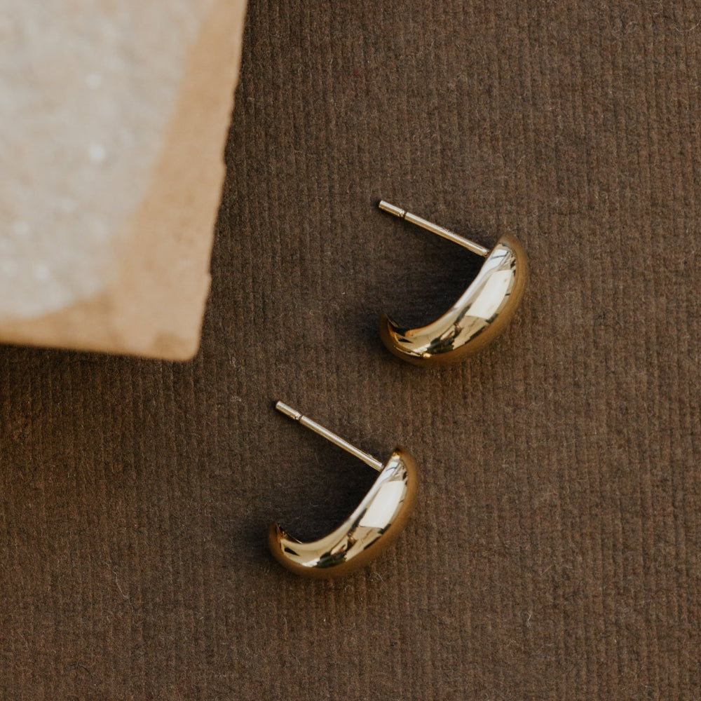 Gold hoop earrings on a brown textured surface