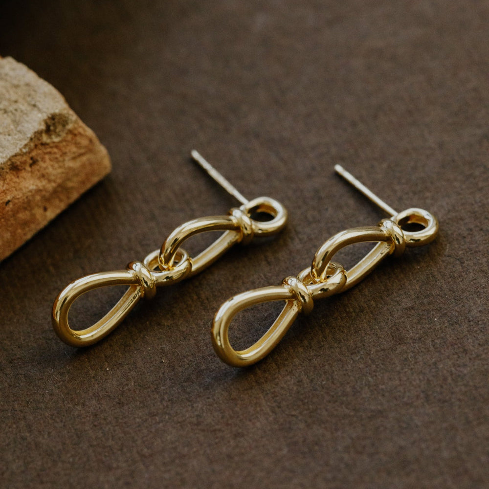 Gold earrings on a brown surface