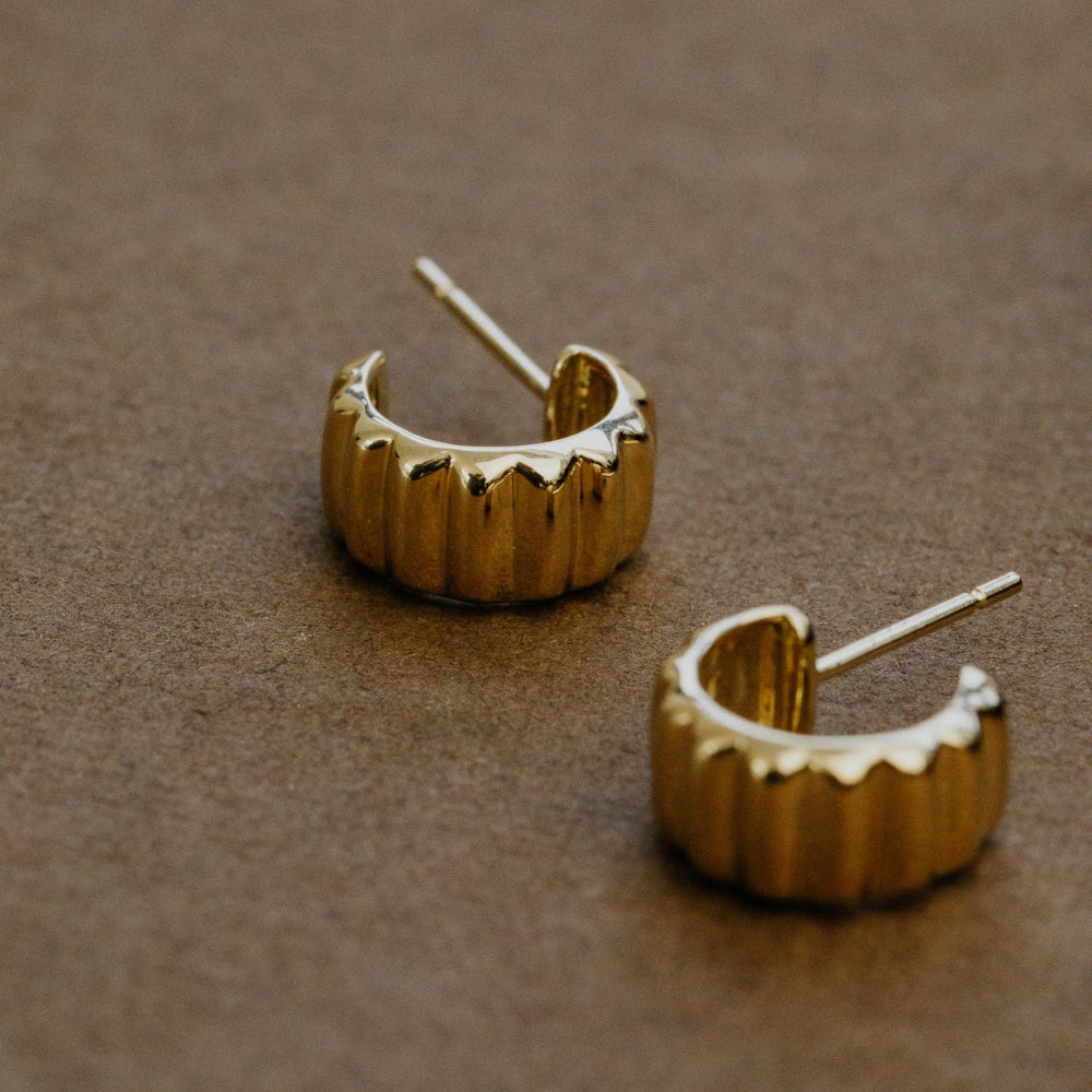 Pair of gold hoop earrings on a brown surface