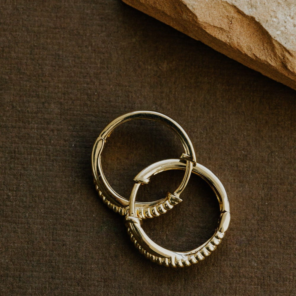 Pair of gold hoop earrings on a brown surface