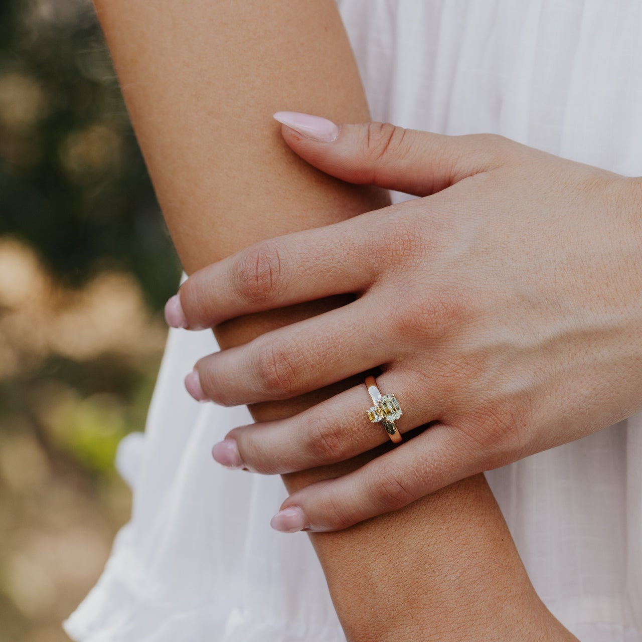 Close-up of a hand wearing a ring with a Montana sapphire on a blurred natural background