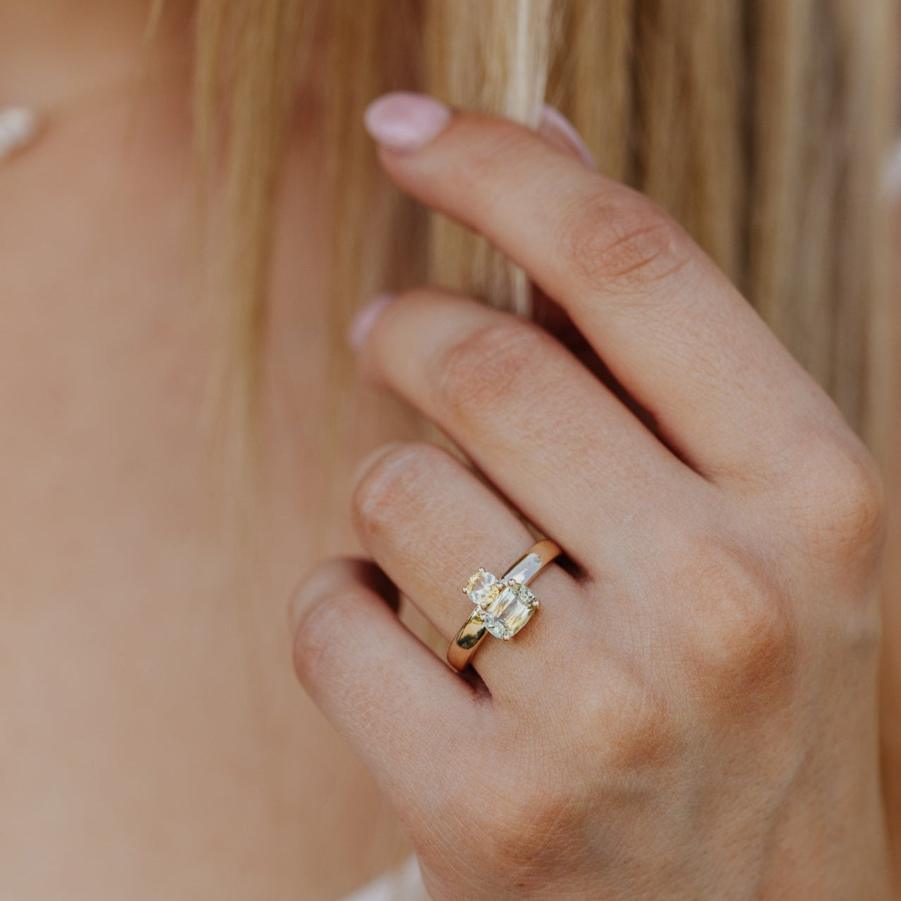 Close-up of a hand wearing a diamond ring with a blurred background