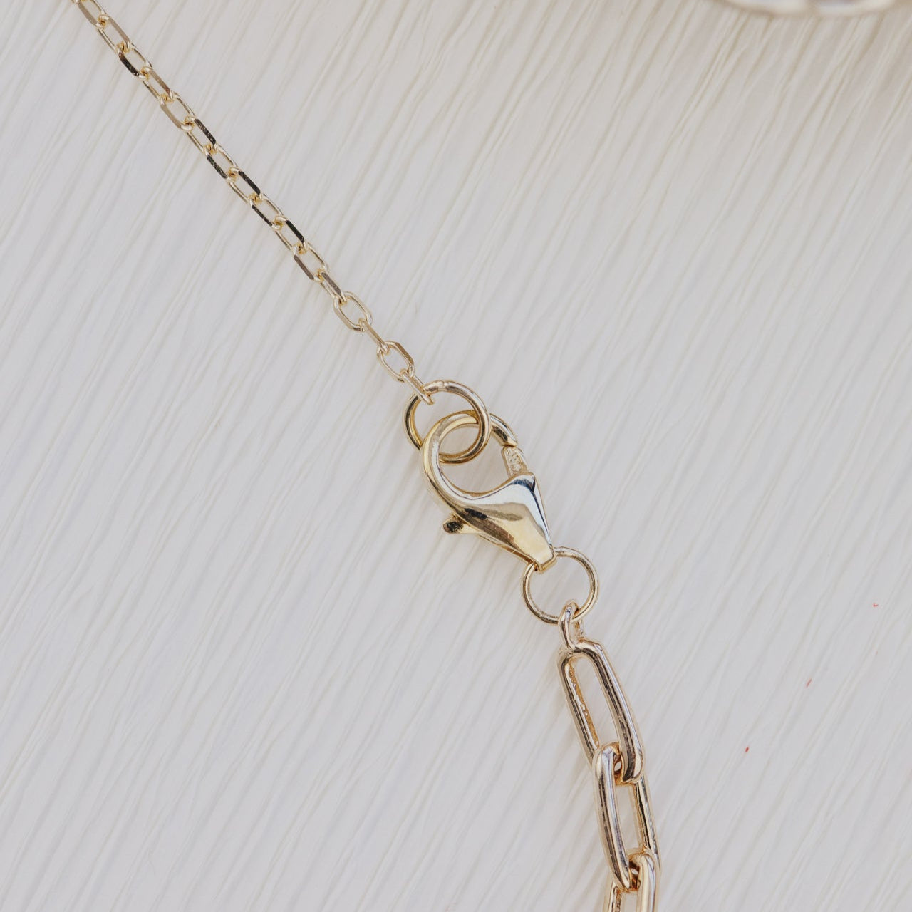 Gold chain necklace on a textured beige surface