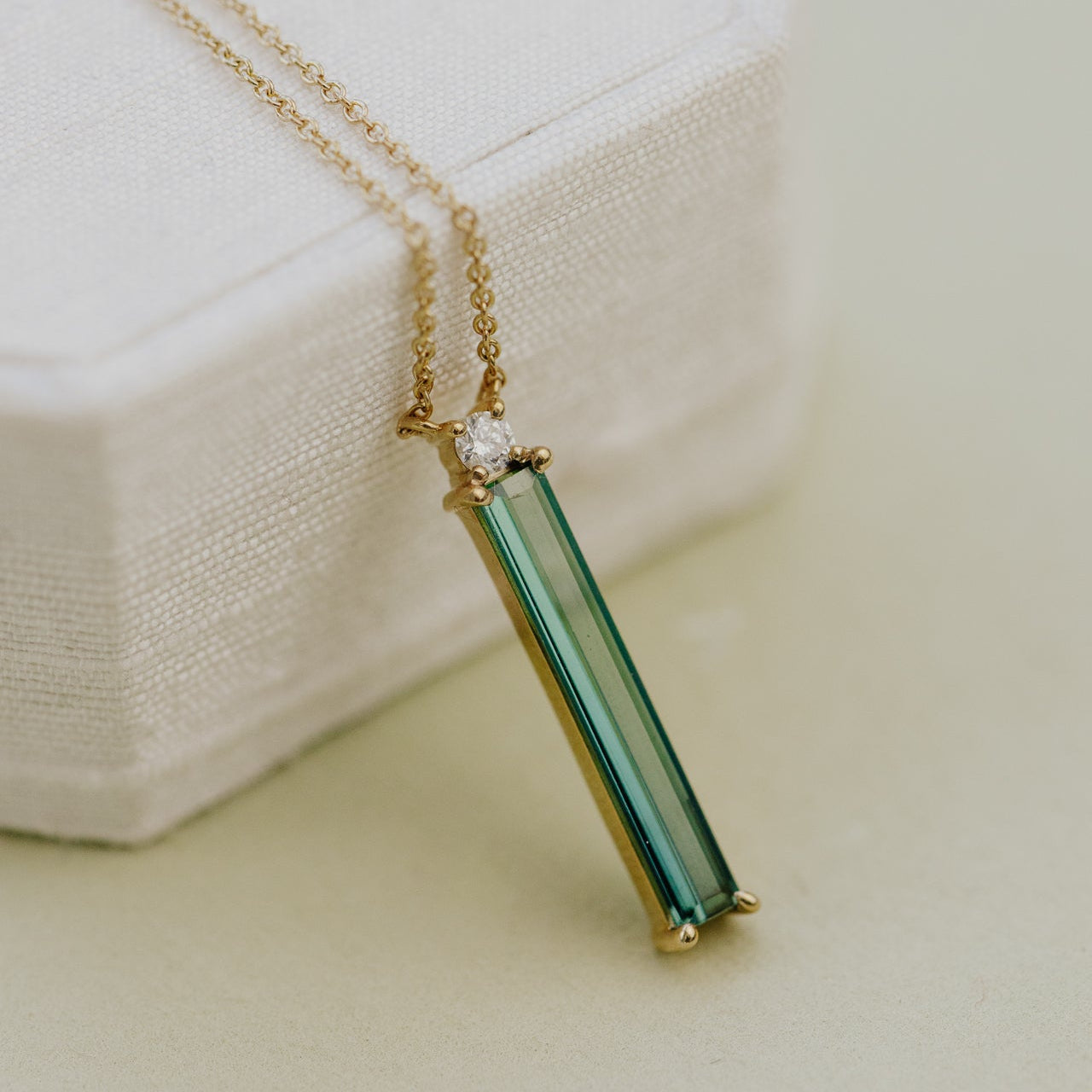 Necklace with a green tourmaline gemstone pendant on a light background