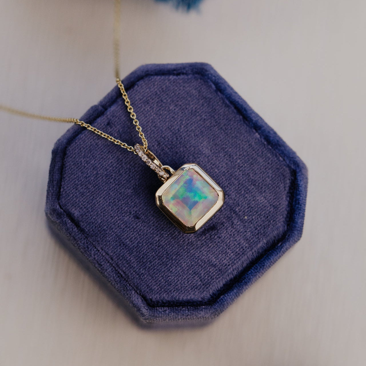 Necklace with a opal pendant on a blue hexagonal jewelry display