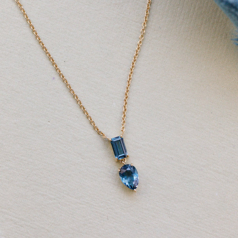 Gold necklace with blue gemstones on a light background