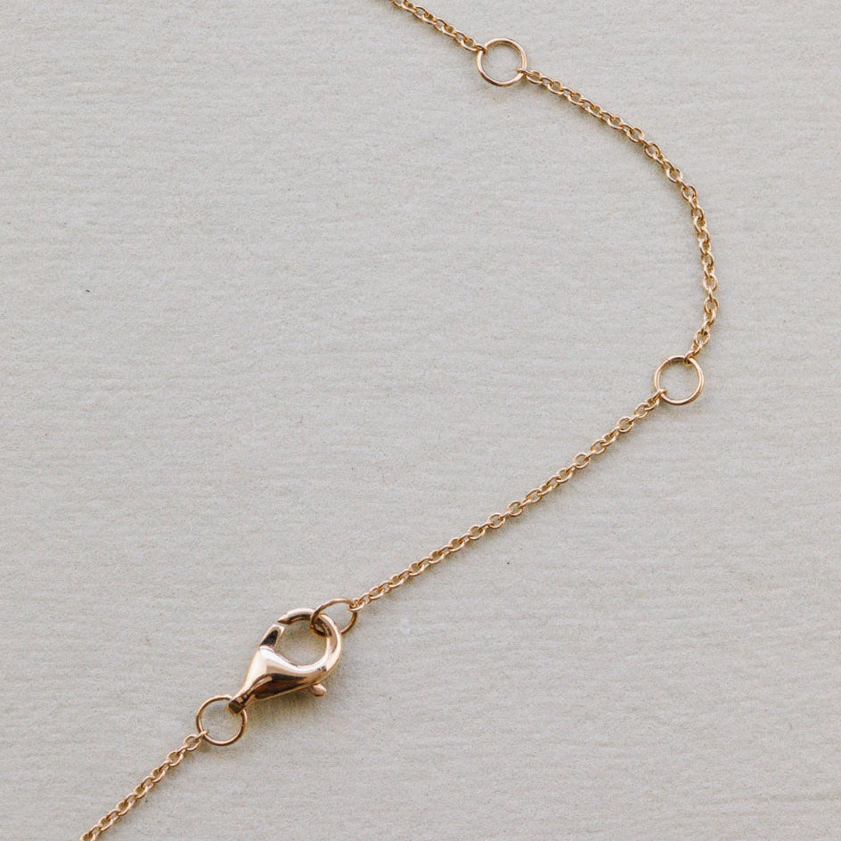 Gold chain necklace with clasp on a light gray background